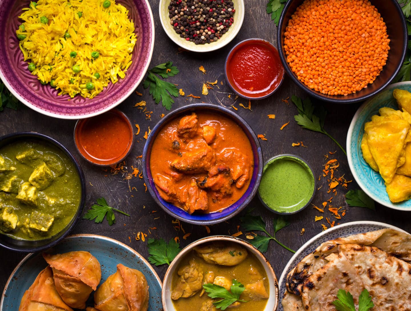 Gros plan sur des plats indiens colorés, avec des bols de paneer, de riz et de poulet au beurre sur une table