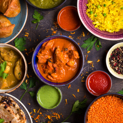 Gros plan sur des plats indiens colorés, avec des bols de paneer, de riz et de poulet au beurre sur une table