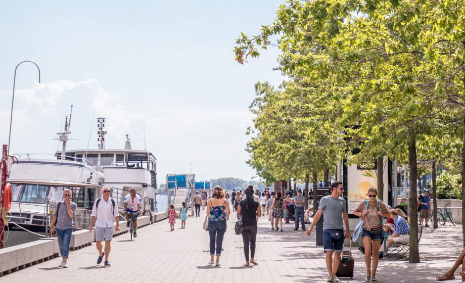 Gens en balade sur le bord de l’eau, avec des bateaux à quai au bord de mer de Toronto